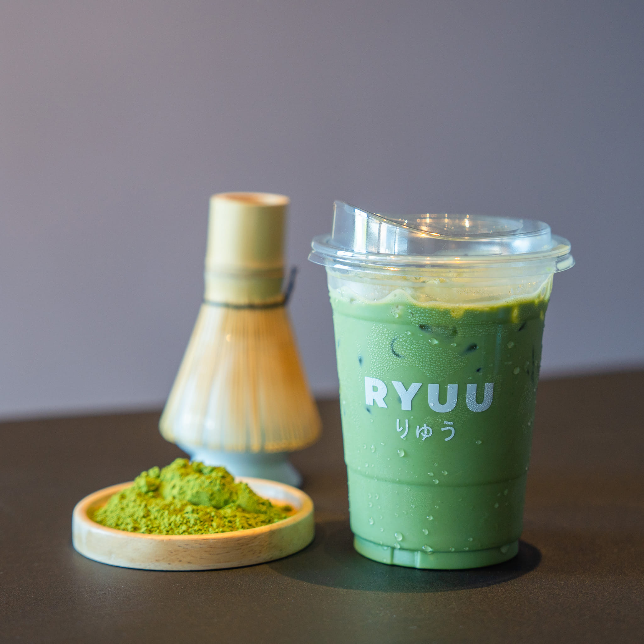 A bamboo chasen whisking bright green matcha